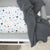 A picture of a bassinet with our Sheffield fitted sheet and a grey throw blanket over the edge. 