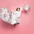 A girl jumping up holding a duvet and a pillow with a red rose pattern.