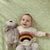 A picture of smiling baby boy holding a soft toy monkey on top of our Banbury pattern. 