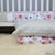 A cot with our Earl Grey and York sheets on it with two matching pillow cases on the floor in front. 
