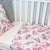 A cot with a Duchess fitted sheet and a Hastings Flat sheet on top. 