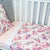A cot with a Duchess fitted sheet and a Hastings Flat sheet on top. 