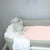 A bassinet with a duchess fitted sheet on it and white blanket and a bunny toy in the corner. 
